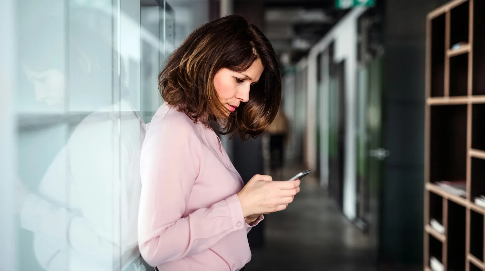 Een collega loopt met de telefoon in de hand over de kantoorvloer